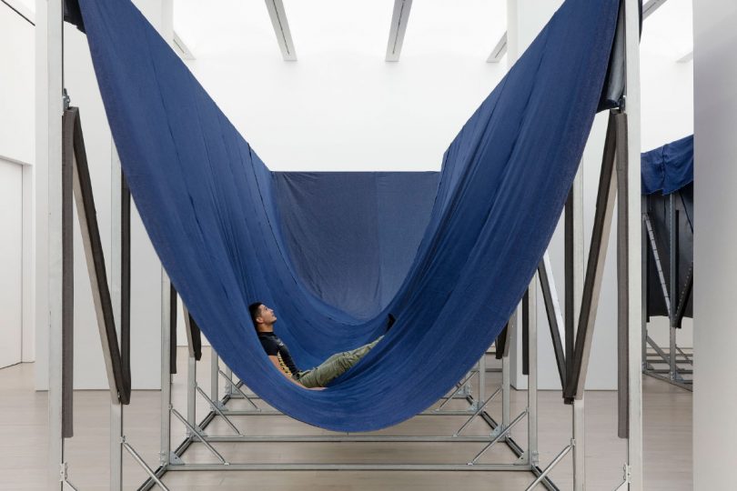 Man relaxes in Paola Pivi's sculpture Free Land Scape