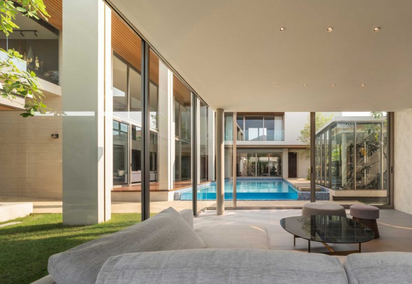 inside view of living room with floor to ceiling glass windows looking out to courtyard and pool