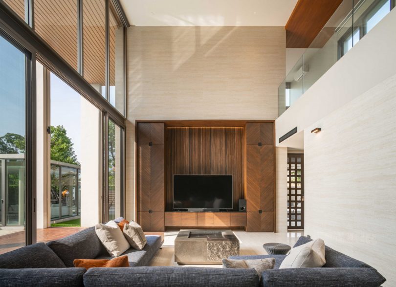 interiérový záběr moderního obývacího pokoje s dvojitou výškou a pohovkou ve tvaru l při pohledu na televizi