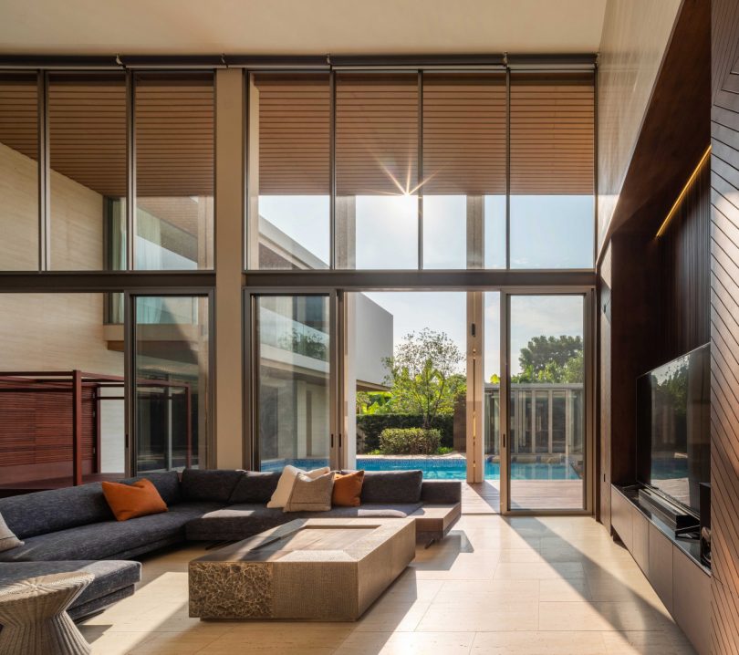 interior shot of modern double-height living rom with l-shaped sofa looking out to pool