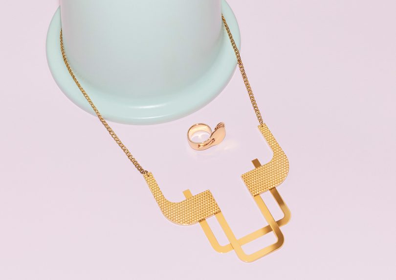 modern necklace and ring on display on colorful plinth