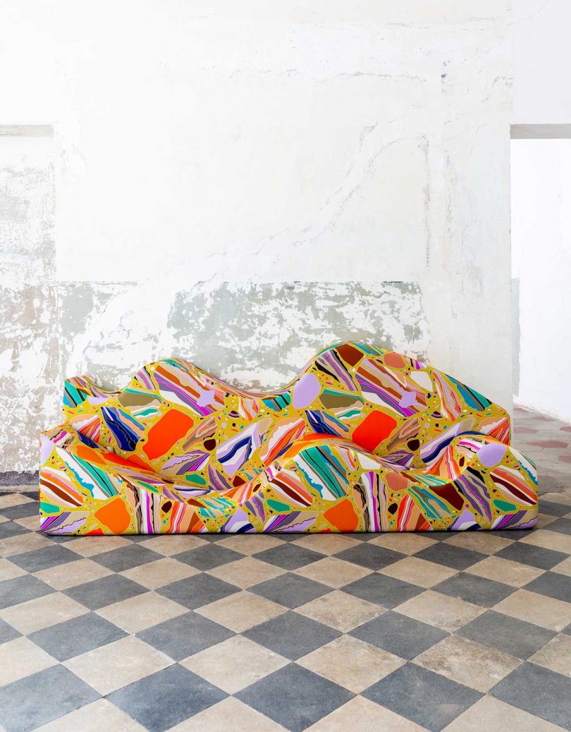 patterned and colorful terrazzo covered curvy sofa against a white wall and checkerboard floor