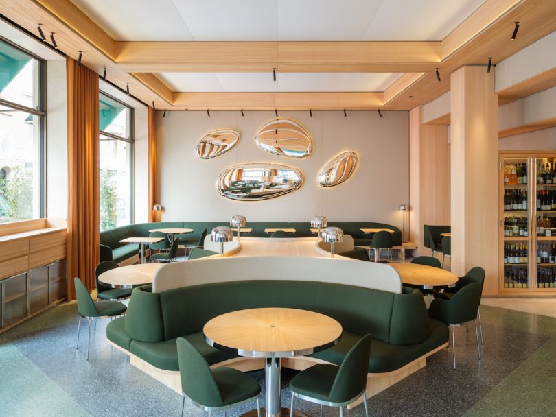 daytime restaurant interior view of dark green seating and light wood tables