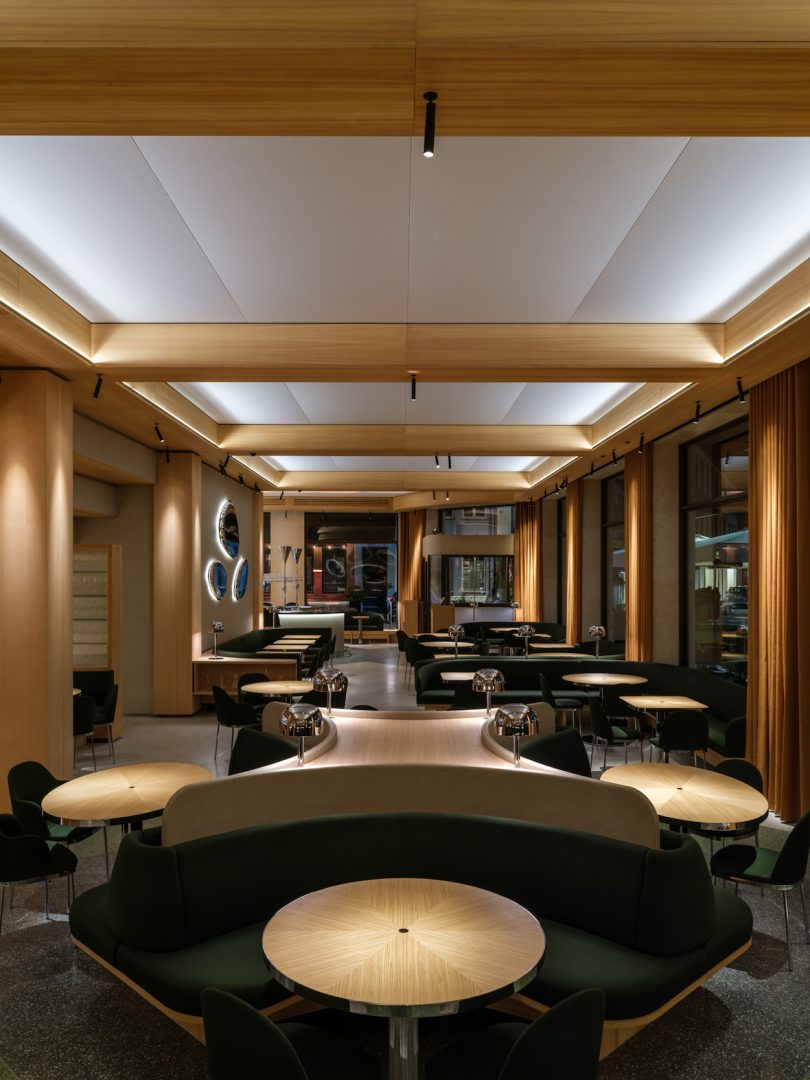 long view of restaurant interior showing various tables and dark green seating