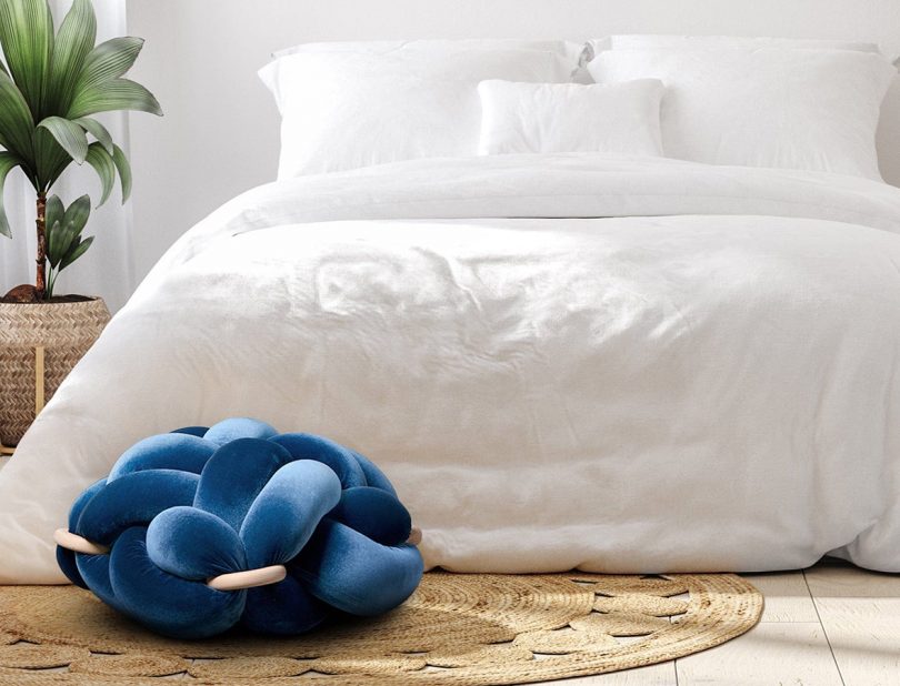 Knot studio blue velvet floor pillow in front of the bed