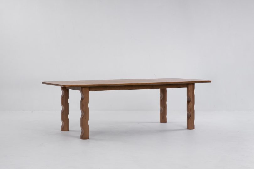 angled side view of dark wood dining table with wavy legs