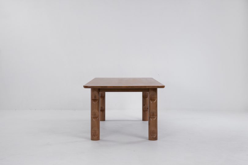 end view of dark wood dining table with wavy legs