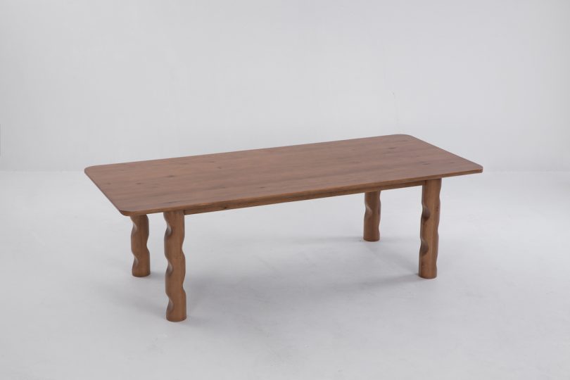 side angled view of dark wood dining table with wavy legs