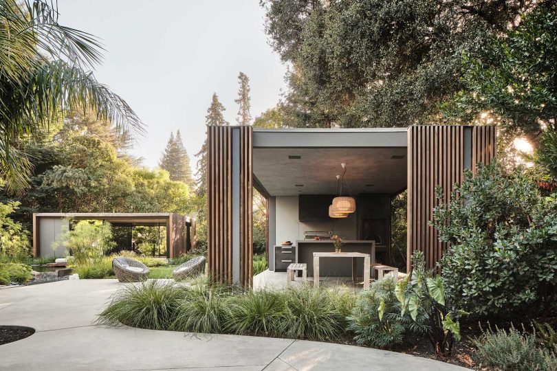 side exterior view of modern pavilion with sliding doors open to reveal kitchen and dining space