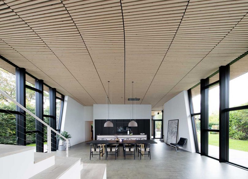 interior view of modern house with wood slatted ceiling, white floors and window walls on both sides