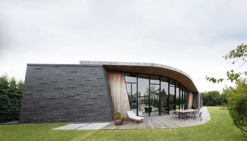 curved exterior shot of modern home with a sloping curve of windows