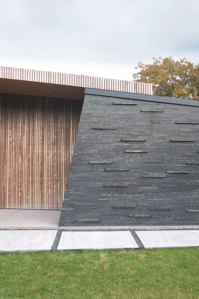 Closeup exterior view of modern house made of gray stone and wood panels