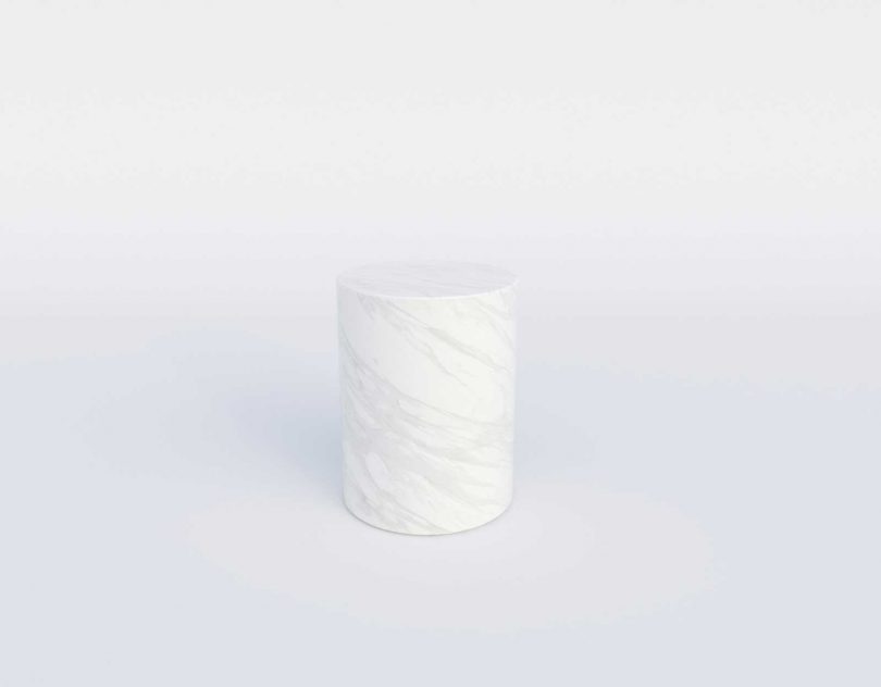 Cylindrical marble side table on a white background