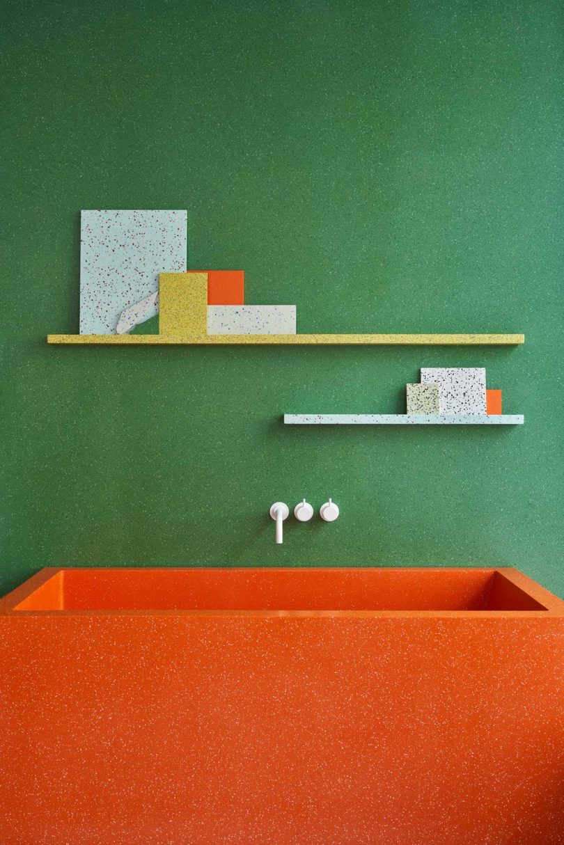interior showroom shot of green wall with orange tub and shelves holding variously colored surface materials