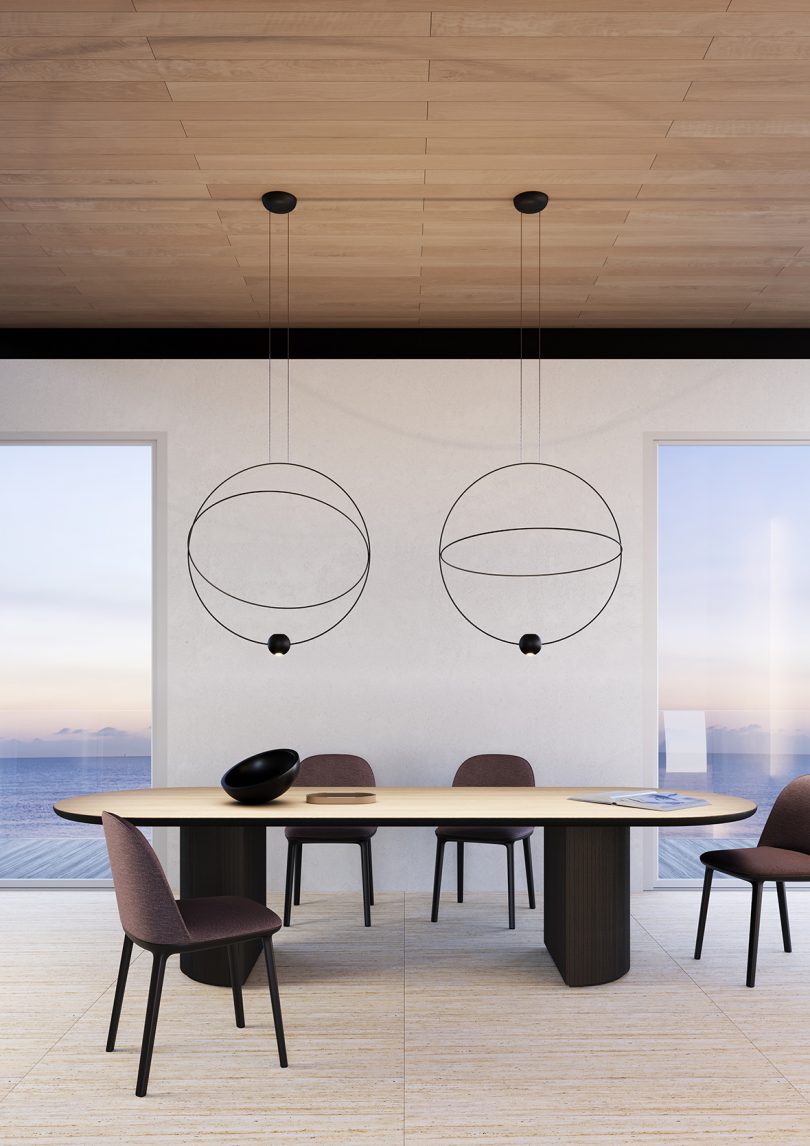 two large orbit-like suspension lamps hang over a dining room table
