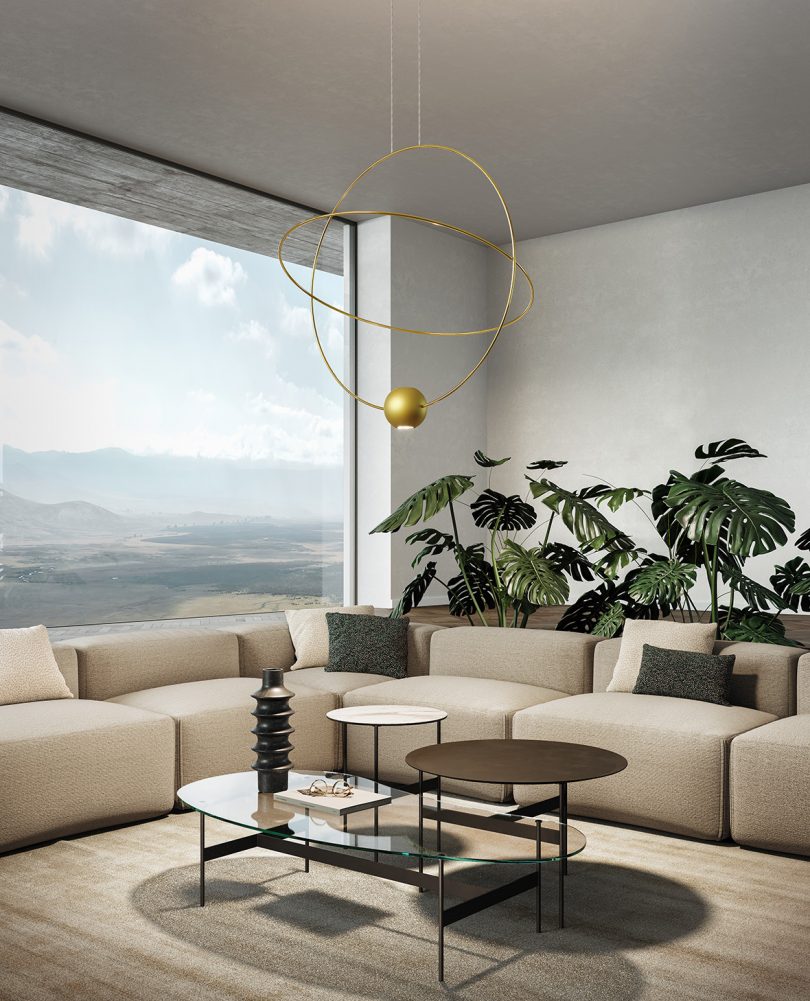 large orbit-like suspension lamp hangs in the middle of a living space with L-shaped sofa and coffee tables