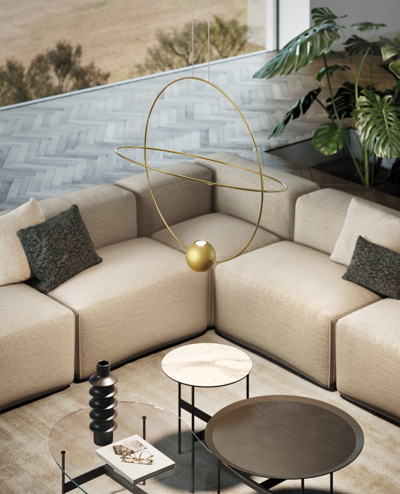 large orbit-like suspension lamp hangs in the middle of a living space with L-shaped sofa and coffee tables