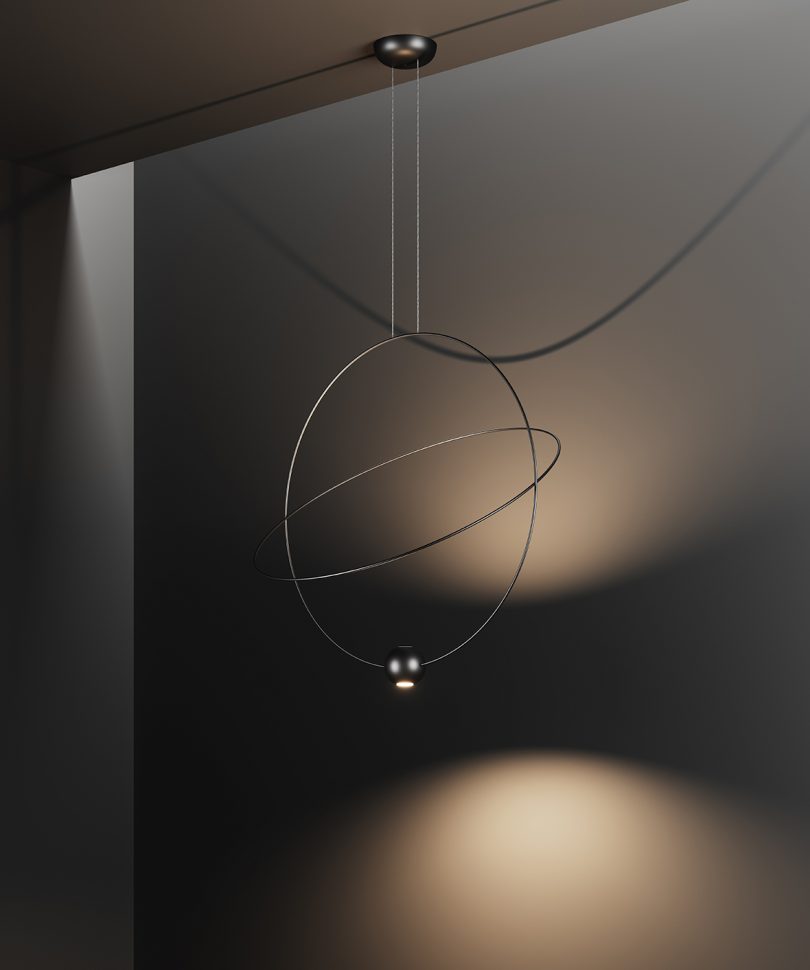large orbit-like suspension lamp hangs against a black background