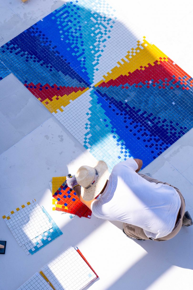 looking down into empty swimming pool with colorful mosaic tile being laid