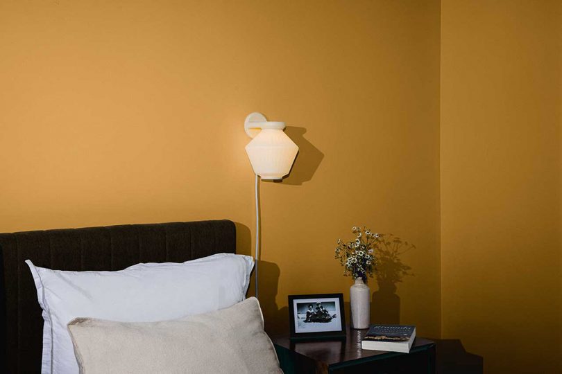 white wall sconce on yellow bedroom wall