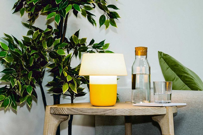 yellow and white table lamp on a side table next to a glass carafe of water