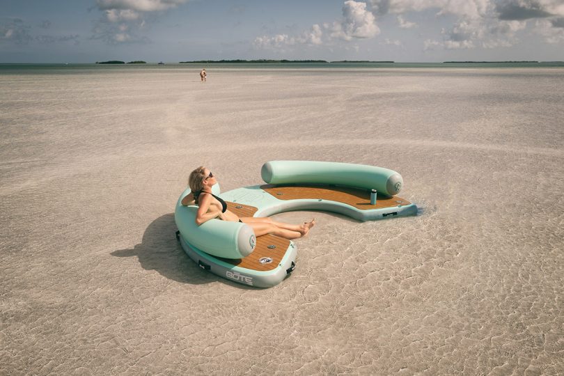 woman seated on a semicircle of floating seating in shallow water
