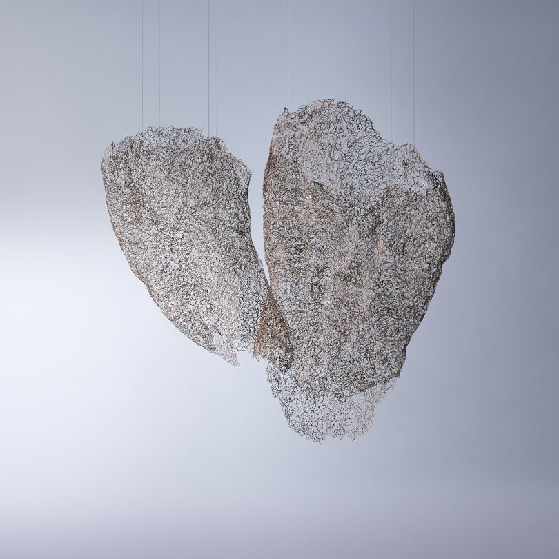 two suspended wire sculptures on a light grey background