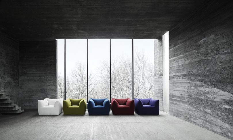 a rainbow of modern armchairs in front of a large wall of windows