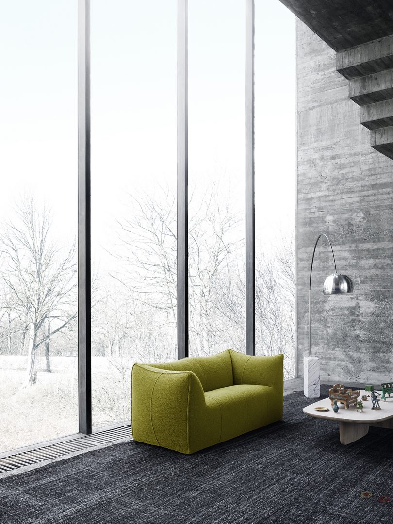 green 2-seater sofa in front of a large wall of windows