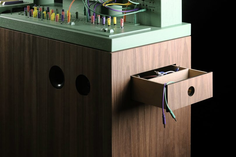 Detail of wood cabinet drawer opened, revealing multicolor cables.