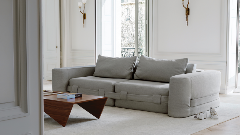 styled interior space with lots of light, a grey sofa and an abstract coffee table