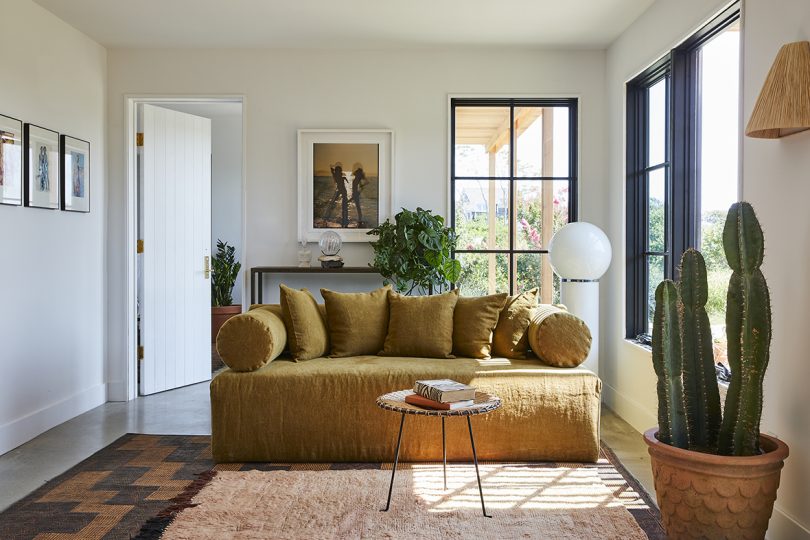 styled interior space with large paned windows, a brown sofa, occasional table, and floor lamp