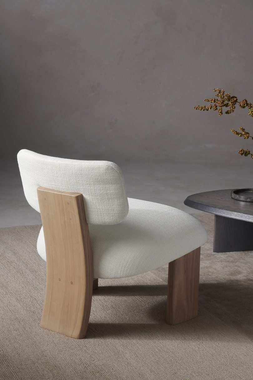 vignette with the back of a white upholstered chair with light wood legs