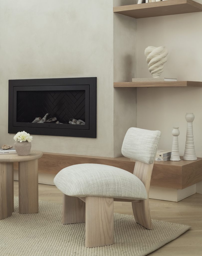 styled interior space with upholstered white chair, side table, and fireplace