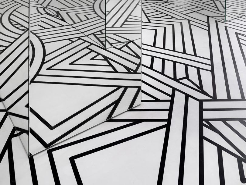 small exhibition filled with a black and white geometric pattern and lots of mirrors