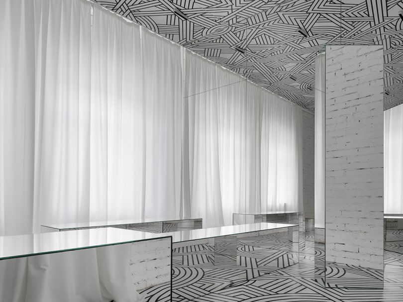 small exhibition filled with a black and white geometric pattern and lots of mirrors