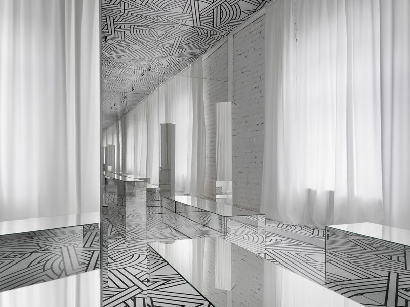 small exhibition filled with a black and white geometric pattern and lots of mirrors