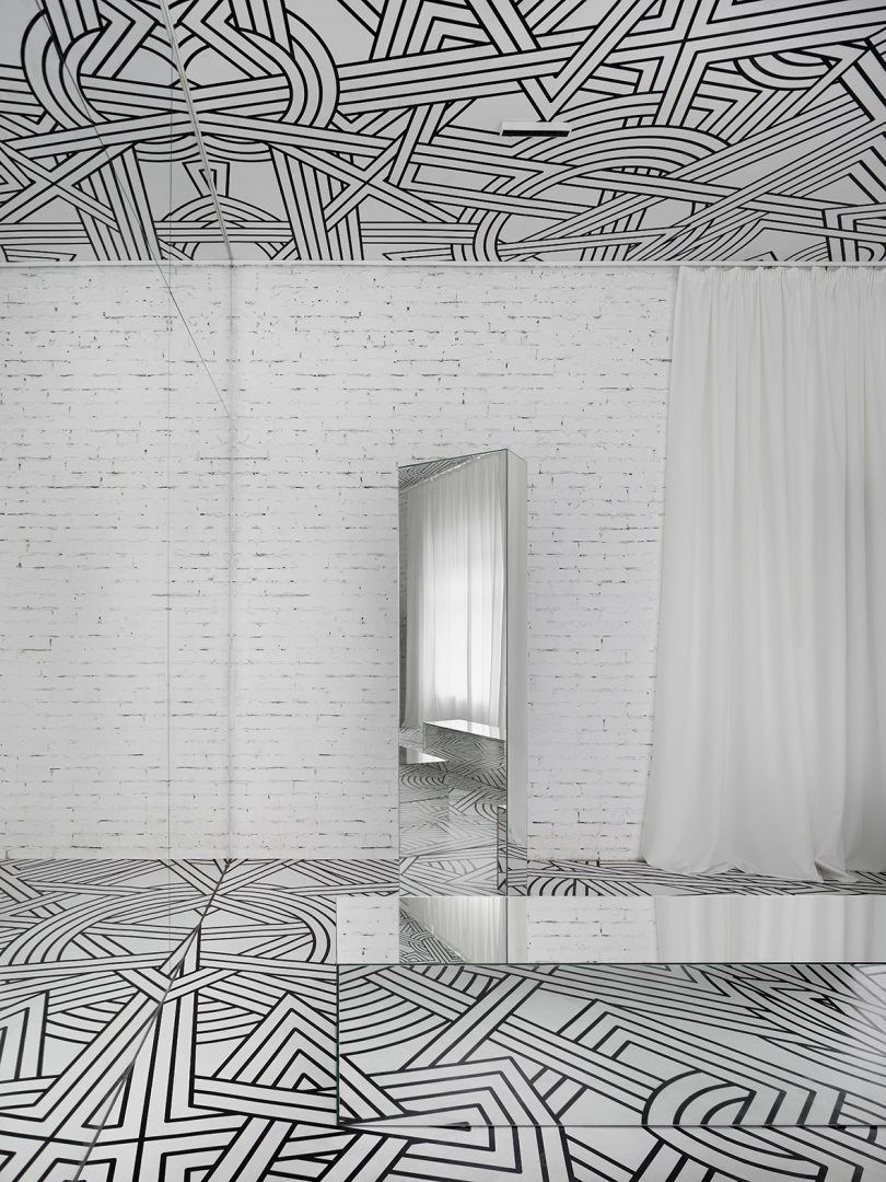 small exhibition filled with a black and white geometric pattern and lots of mirrors