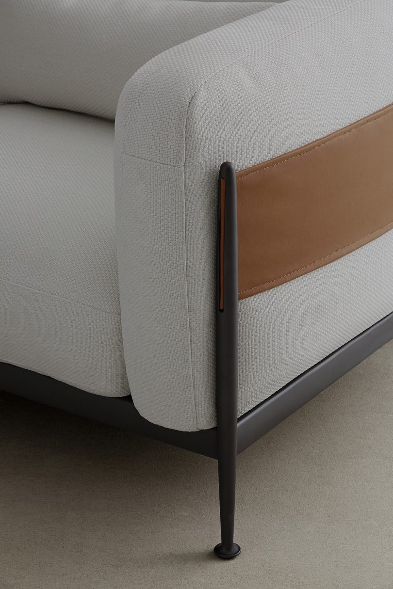 detail of off white sofa with black metal structure and surrounding "belt"
