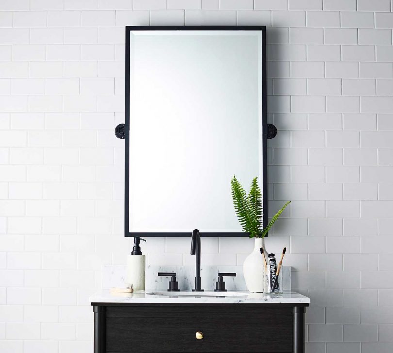 black edged mirror above a bathroom sink in styled space