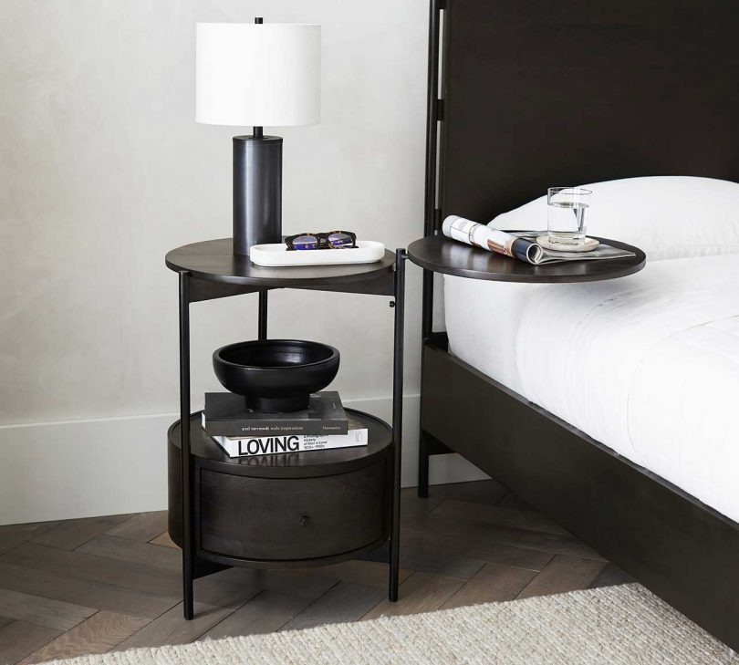 dark wood nightstand with round arm extended in styled bedroom