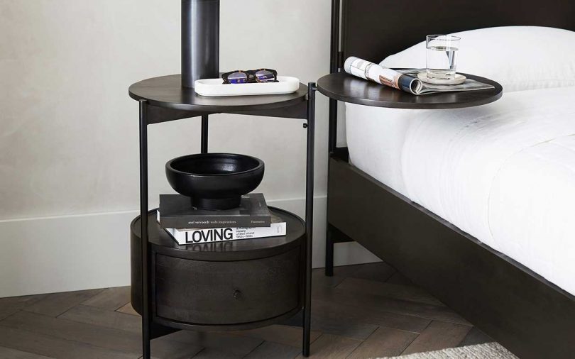 dark wood nightstand with round arm extended in styled bedroom