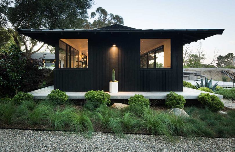 exterior view of modern box-like home with black exterior and windows