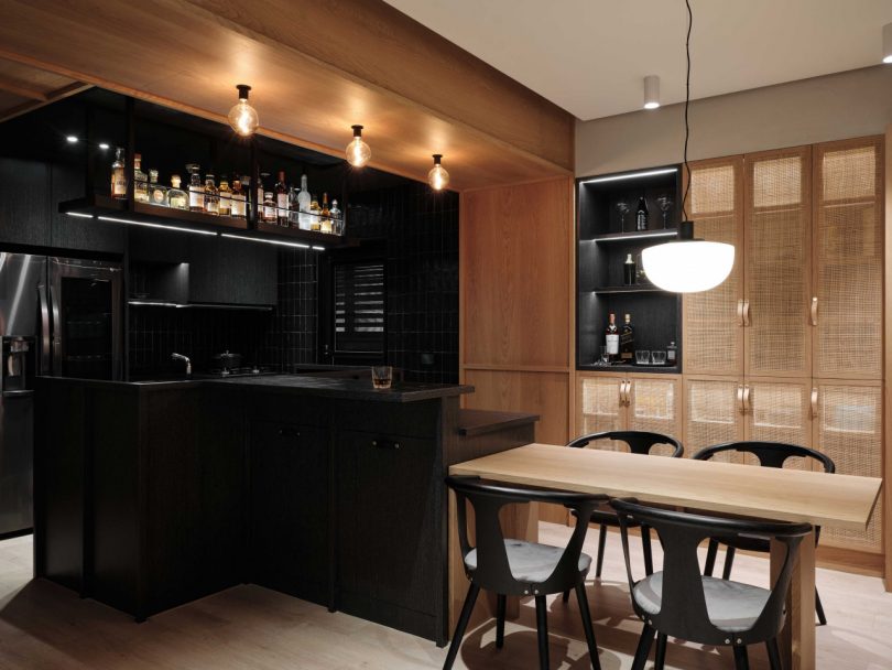 interior shot of modern apartment kitchen in all black and dining area in natural materials