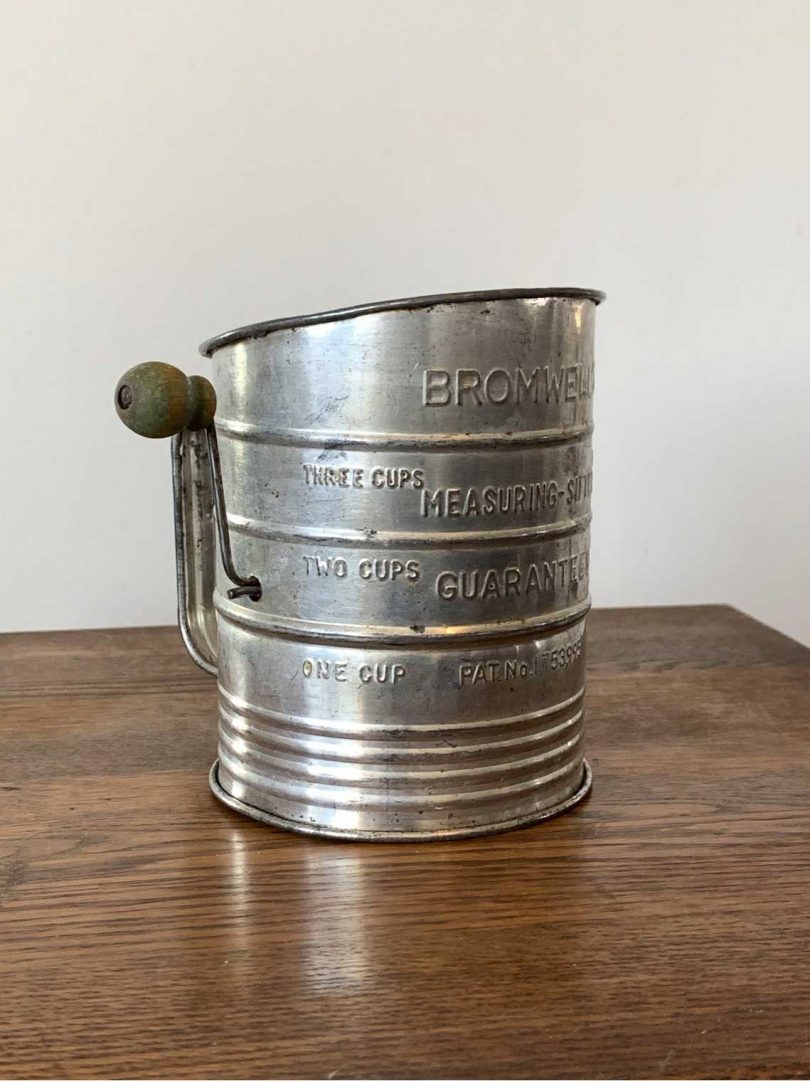 vintage stainless steel sifter on wooden table