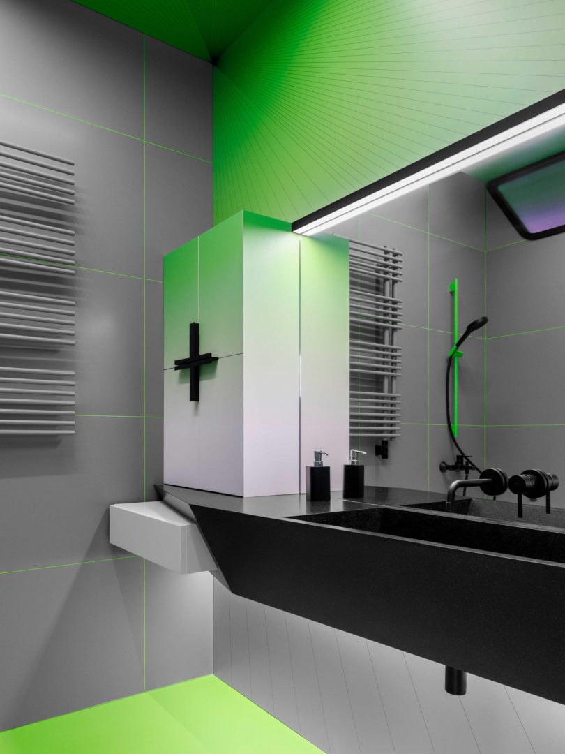 angled view of modern bathroom in shades of grey and black with gradient green accent