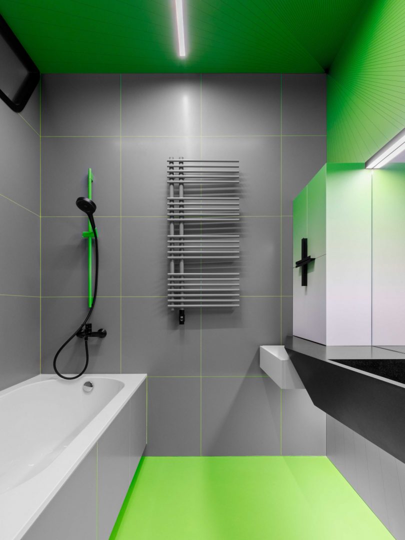 view of modern bathroom in shades of grey and black with gradient green accent