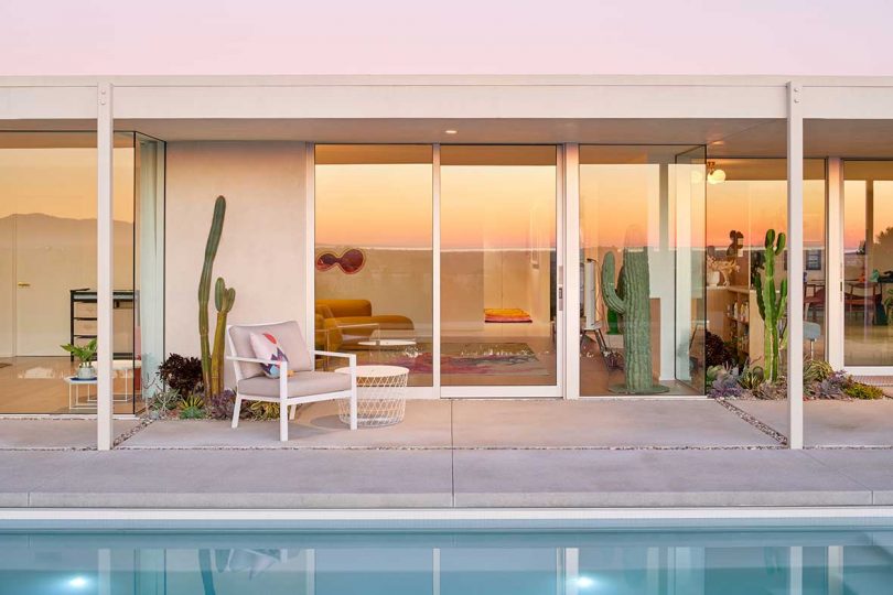 exterior rear view of mid-century modern house with pool and sunset reflecting in windows