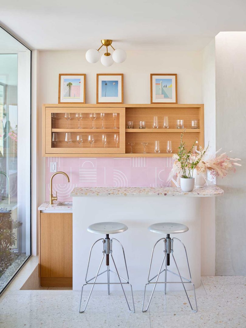 interior of a mid century modern home with a home bar with pink tiles and wooden shelves