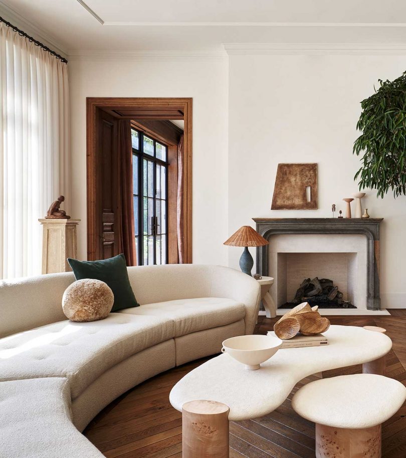 modern living room with curved beige sofa, fireplace and sculptural coffee table